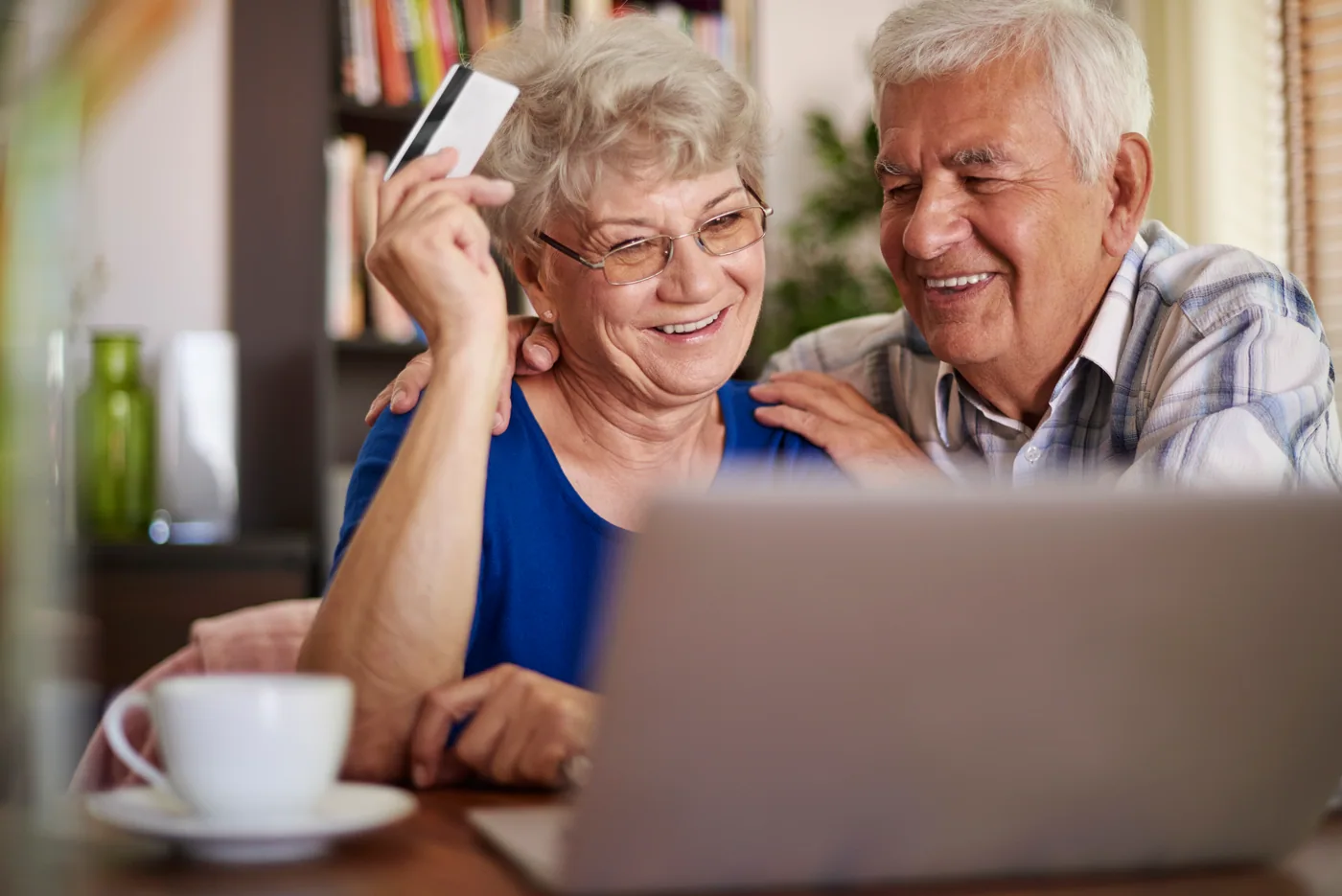 Casal sênior sorrindo enquanto contrata crédito pela internet com tranquilidade